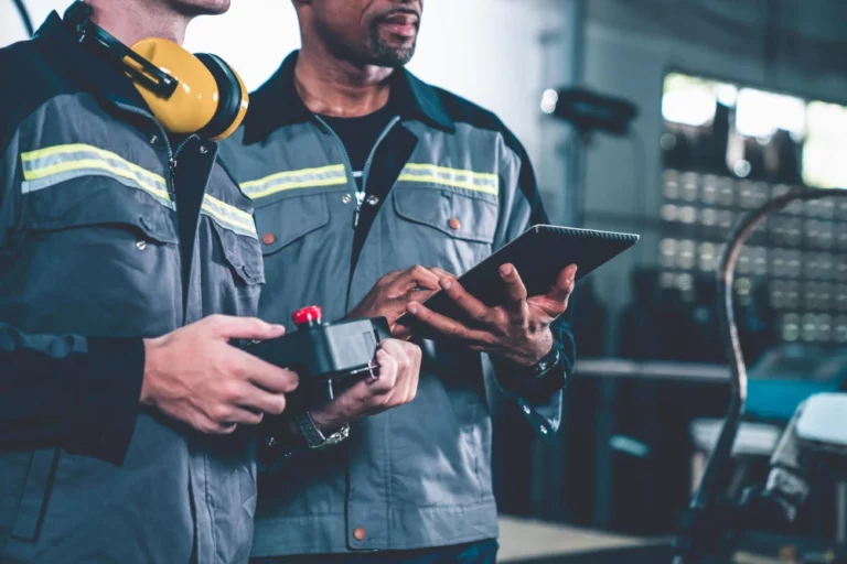 Profissionais em um ambiente de manutenção industrial, discutindo estratégias e tecnologia para como empreender no setor. Trabalho em equipe e inovação.