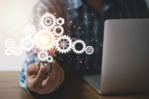 Imagem que representa o conceito de empreendedorismo técnico, mostrando uma mão segurando uma lâmpada com engrenagens ao fundo, simbolizando ideias inovadoras na revenda de peças e equipamentos industriais.