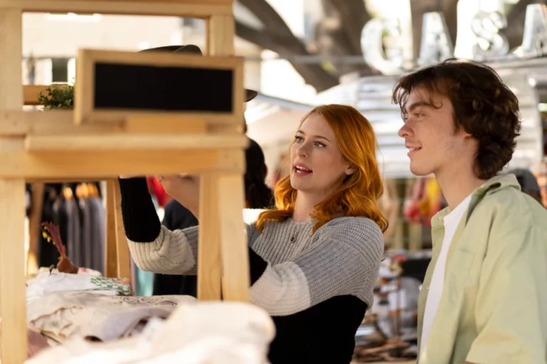 Jovens interagindo com um expositor personalizado em uma feira ou evento, destacando a criatividade na apresentação de marcas para atrair clientes e aumentar vendas.