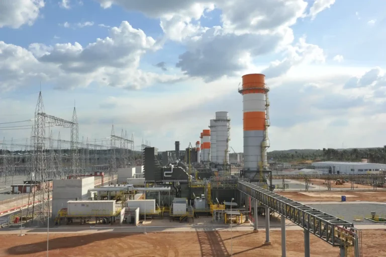 Imagem de uma usina industrial com torres de ventilação e linhas de distribuição de energia, ilustrando erros operacionais que aumentam custos na indústria.