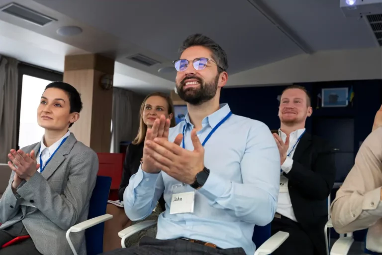 Participantes de um evento B2B de negócios e inovação assistindo a uma apresentação ou palestra, demonstrando interesse e networking especializado.