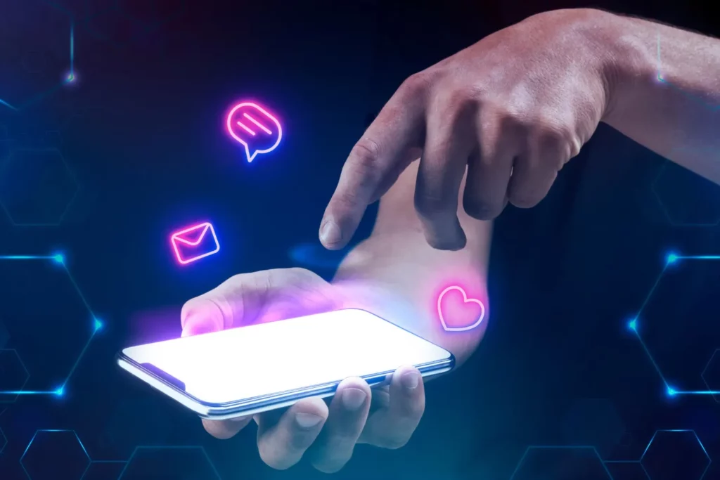 Mãos usando um smartphone com ícones neon de conversa, e-mail e corações no fundo digital, simbolizando o processo de conversão de visitantes em clientes no ambiente online. Como transformar visitantes em clientes: A Jornada de compra no ambiente digital